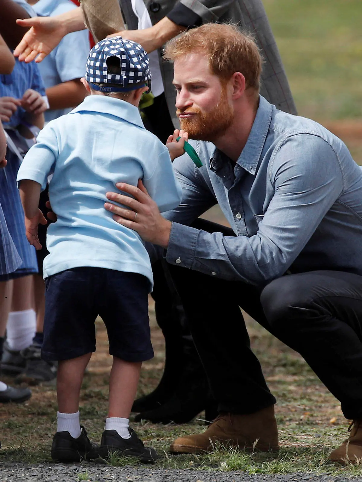 17.10.2018, Australien, Dubbo: Schüler Luke Vincent von der Buninyong Public School fasst Prinz Harry (r) an den Bart. Prinz Harry und seine Frau Meghan sind auf ihrer ersten offiziellen gemeinsamen Auslandsreise seit der Hochzeit im Mai und machen eine 16-Tägige Tour durch Australien, Neuseeland, die Fidschi-Inseln und das Königreich Tonga. Foto: Phil Noble/Reuters POOL/AP/dpa +++ dpa-Bildfunk +++
