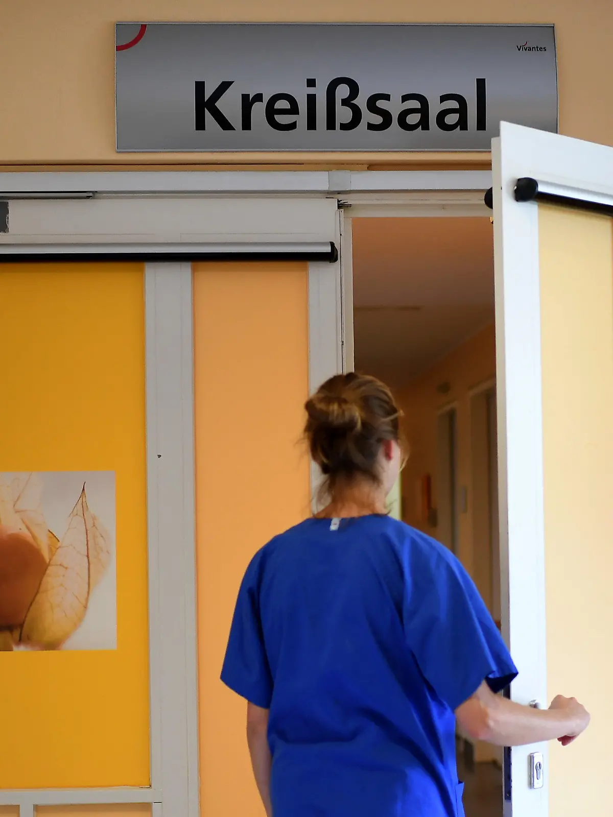 ARCHIV - 12.07.2018, Berlin: Eine Mitarbeiterin steht vor einem Kreißsaal in einem Krankenhaus. Das Statistische Bundesamt äußert sich am 15.02.2023 zu Krankenhaus-Entbindungen per Kaiserschnitt und Geburtshilfe in Deutschland und international im Jahr 2021. Foto: Britta Pedersen/dpa-Zentralbild/dpa +++ dpa-Bildfunk +++
