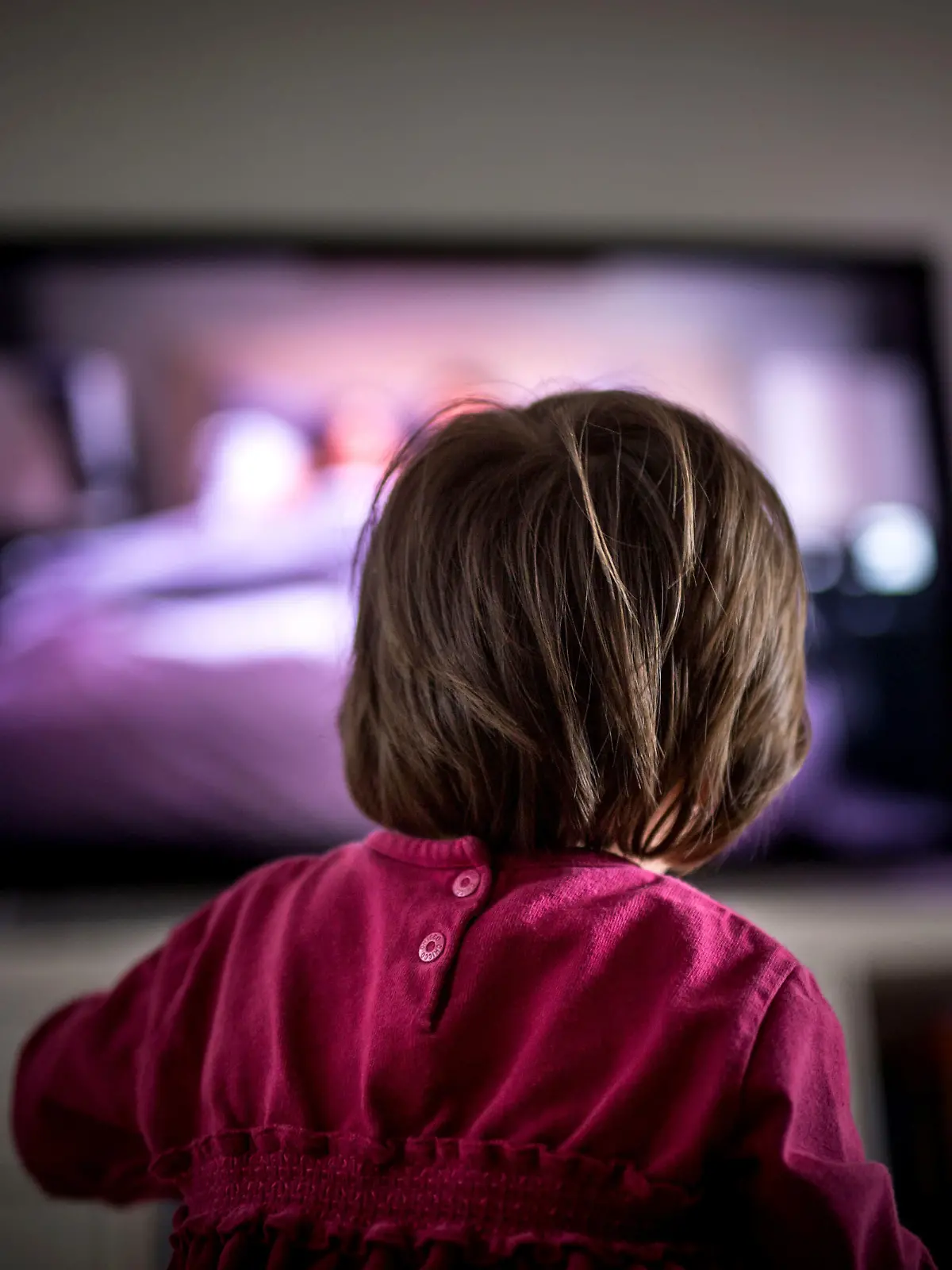 ILLUSTRATION - Ein zweijähriges Kind sitzt am 28.11.2014 in Frankfurt am Main (Hessen) vor einem großen Fernsehgerät. Fernsehen löst nach einer Studie bei vielen Kindern Ängste oder gar Alpträume aus. Foto: Frank Rumpenhorst/dpa (zu dpa: "Zombies und Schockmomente: Fernsehen macht Kindern oft Angst" vom  28.11.2014)