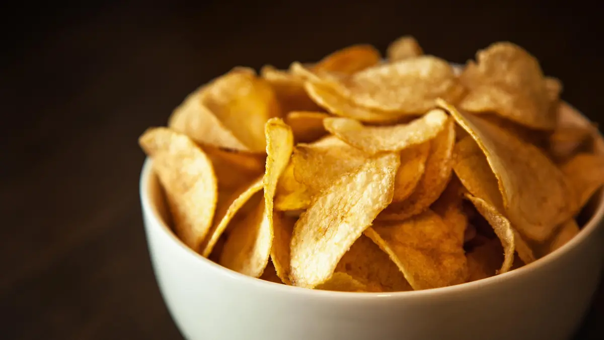 Crispy potato chips in white bowl