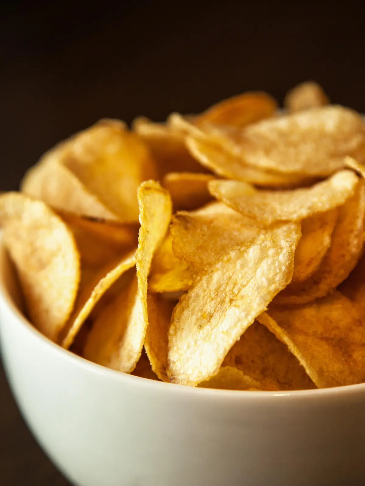 Crispy potato chips in white bowl