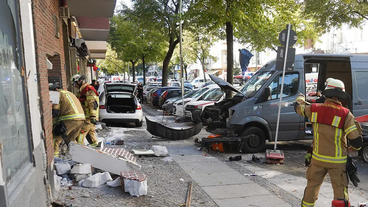 05.10.2018, Berlin: Einsatzkräfte der Feuerwehr stehen an einer beschädigten Hauswand. Das weiße Fahrzeug soll in ein Cafe gefahren sein und dabei fünf Personen verletzt haben. Foto: Jörg Carstensen/dpa +++ dpa-Bildfunk +++
