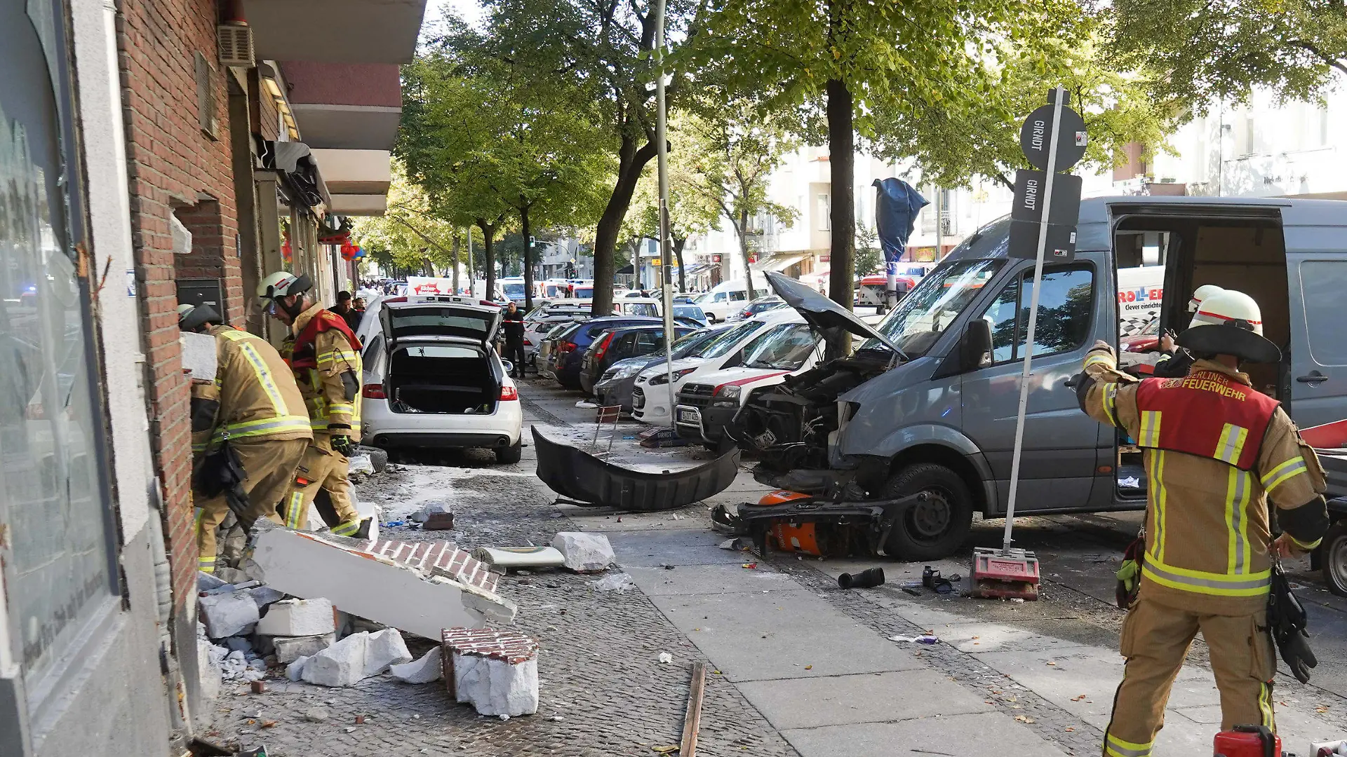 05.10.2018, Berlin: Einsatzkräfte der Feuerwehr stehen an einer beschädigten Hauswand. Das weiße Fahrzeug soll in ein Cafe gefahren sein und dabei fünf Personen verletzt haben. Foto: Jörg Carstensen/dpa +++ dpa-Bildfunk +++