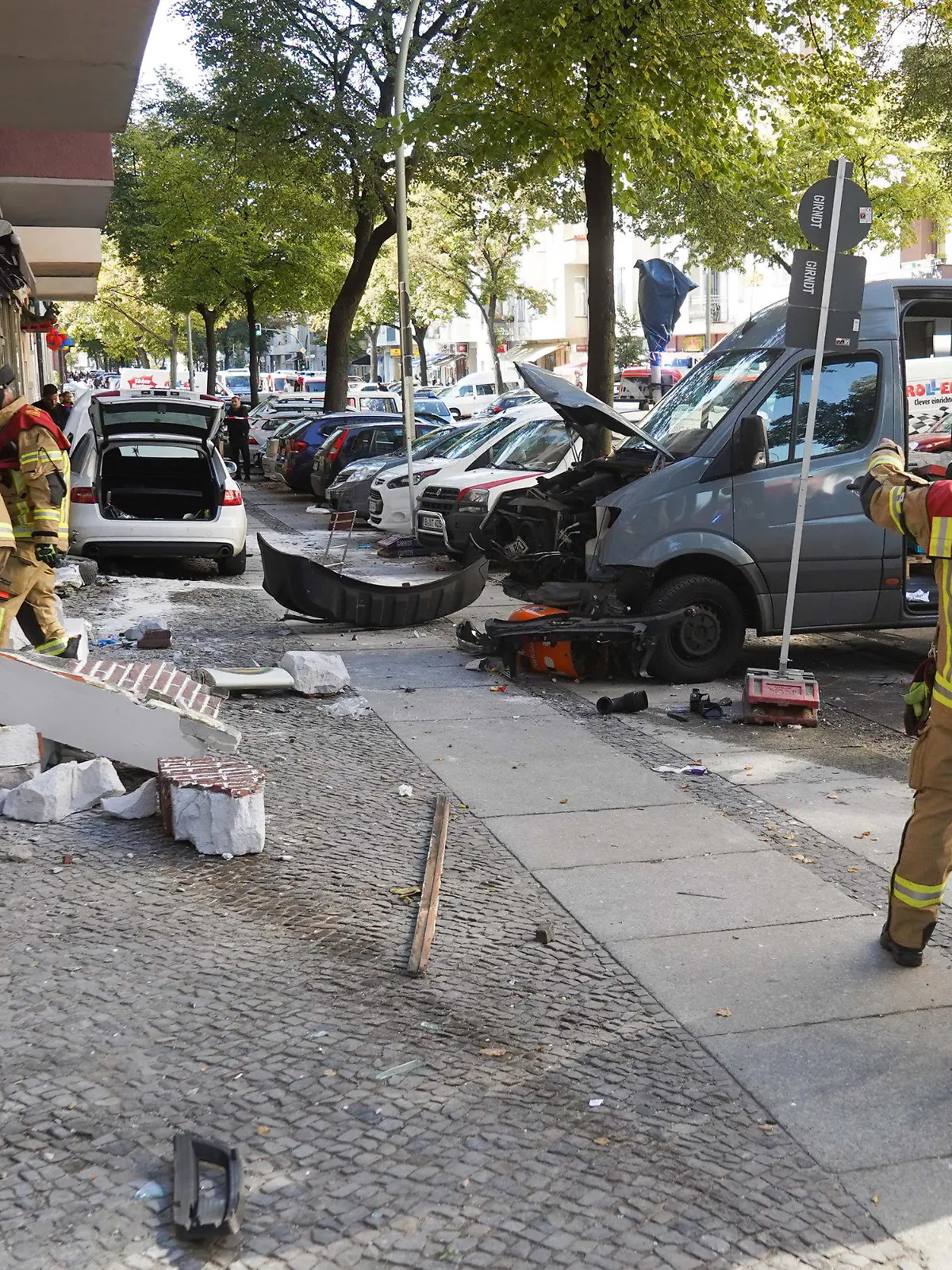 05.10.2018, Berlin: Einsatzkräfte der Feuerwehr stehen an einer beschädigten Hauswand. Das weiße Fahrzeug soll in ein Cafe gefahren sein und dabei fünf Personen verletzt haben. Foto: Jörg Carstensen/dpa +++ dpa-Bildfunk +++