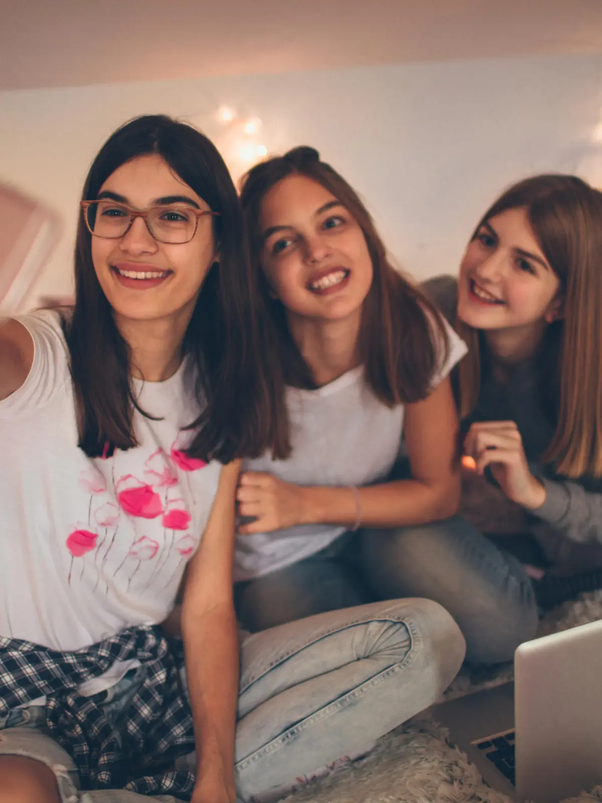 Drei glückliche Mädchen im Teenageralter mit Smartphones im Kinderzimmer