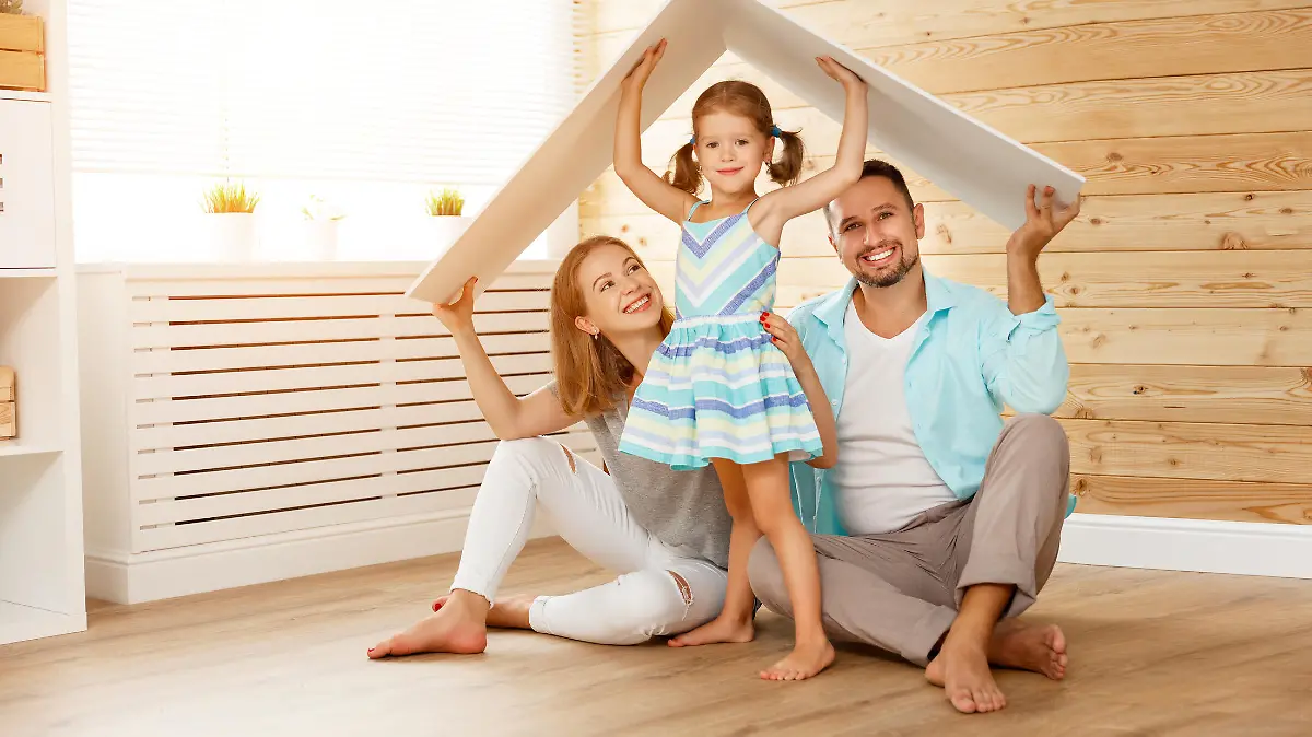 Familie mit einem Kind in neuem Zuhause mit symbolischem Dach über dem Kopf.
