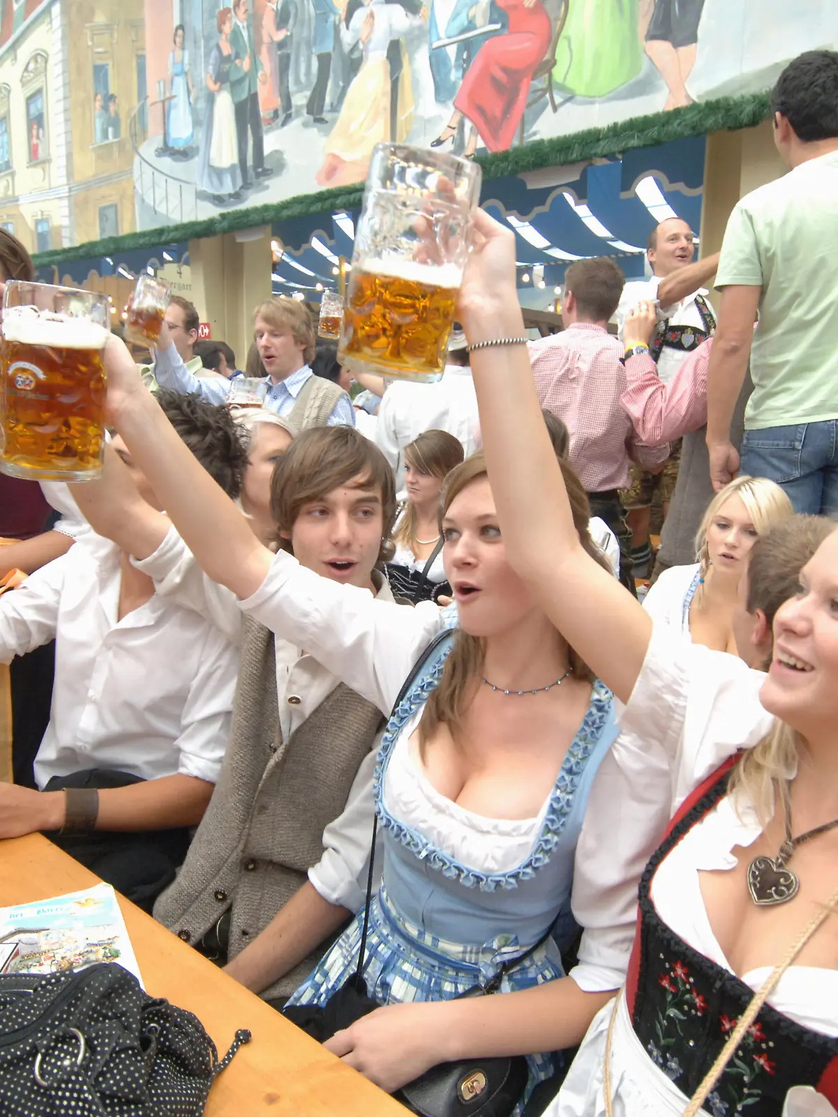 Junge Besucher stoßen bei Oktoberfest mit Maß Bier an