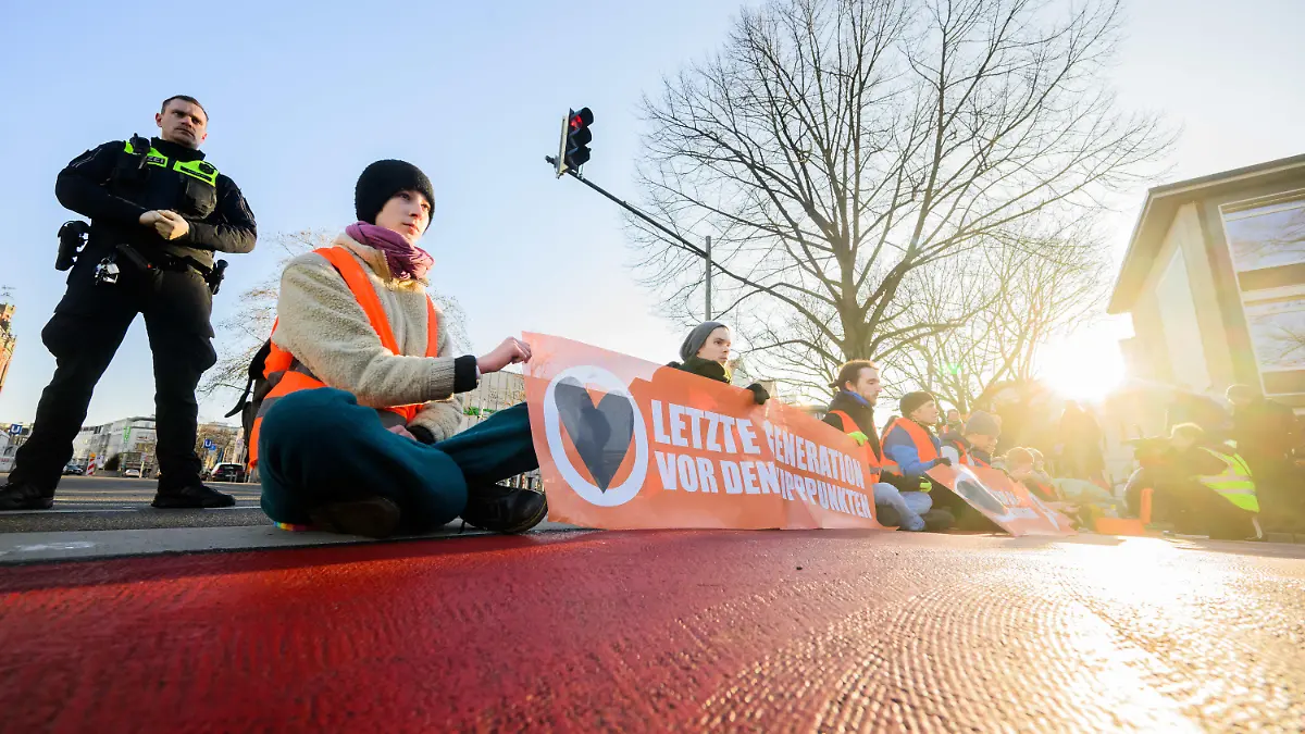 dpatopbilder - 14.02.2023, Niedersachsen, Hannover: Aktivisten der Gruppierung «Letzte Generation» haben sich in der Innenstadt teils auf der Straße festgeklebt und blockieren den Verkehr. Foto: Julian Stratenschulte/dpa +++ dpa-Bildfunk +++