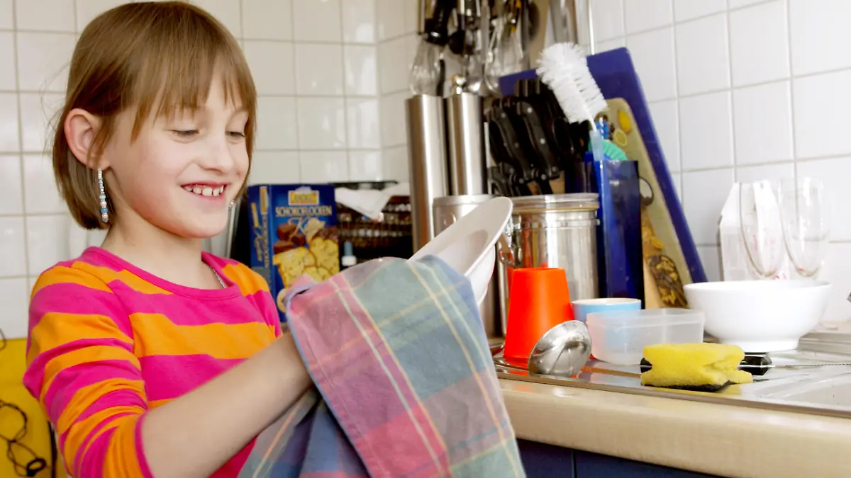 Ein Mädchen (8 Jahre) hilft bei der alltäglichen Hausarbeit. Das Kind übernimmt in der Familie selbständig kleine und grössere Aufgaben im Haushalt. Hier: beim Abtocknen der frisch gespülten Teller mit einem Küchentuch in der Küche. Troisdorf, Nordrhein-Westfalen, Deutschland, 13.03.2007
