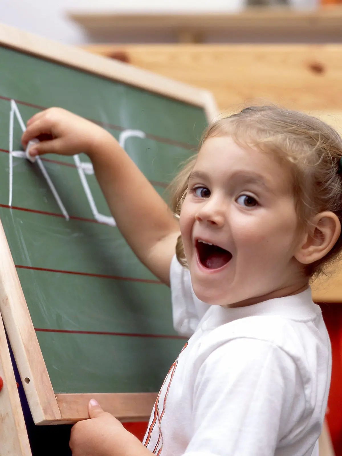 Mit Eifer schreibt dieses fünfjährige Mädchen bei dem gestellten Symbolbild die Buchstaben A B und C mit Kreide auf eine Schultafel, aufgenommen am 5.9.2003. Angesichts zunehmender Leseschwäche bei Kindern fordert die Stiftung Lesen in den Kindergärten verbindliche Tests zur Sprachfähigkeit. Nur auf Grundlage solcher Untersuchungen könne den Kindern frühzeitig gezielt und individuell geholfen werden. Rund 20 Prozent der Einschulungskinder haben Sprachentwicklungsprobleme, so die Stiftung. Später Folgen sind gravierende Lese- und Schreibeschwächen auch nach mehrjährigem Schulbesuch. Etwa vier Millionen Erwachsene in Deutschland können Schätzungen zufolge nicht richtig lesen und schreiben, obwohl sie die Schule besucht haben.