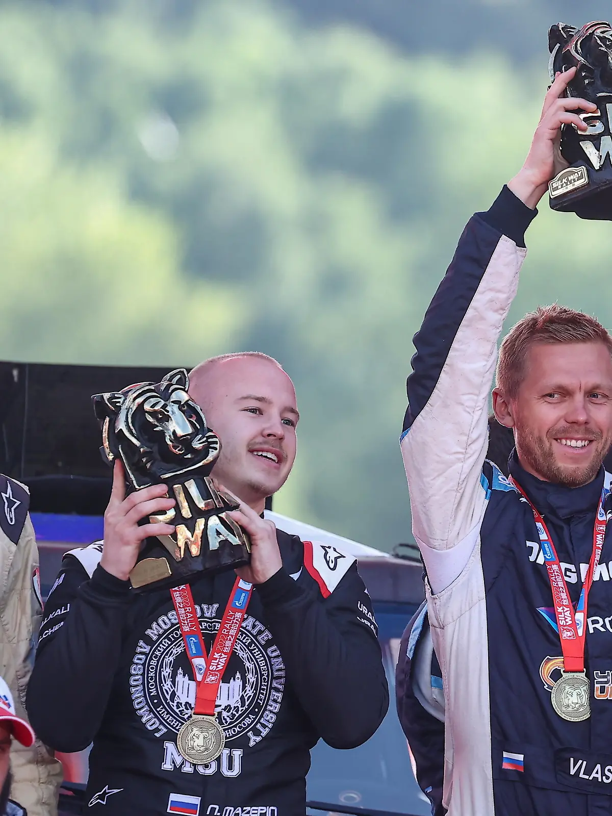 DIESES FOTO WIRD VON DER RUSSISCHEN STAATSAGENTUR TASS ZUR VERFÜGUNG GESTELLT. [MOSCOW, RUSSIA - JULY 16, 2022: Drivers Nikita Mazepin (2nd L) and Anton Vlasyuk (L) of the Snag Racing Team, the gold winners in the All-Terrain Vehicles category, celebrate during an award ceremony after the finish of the Silk Way Rally, a rally raid from Astrakhan to Moscow, at Moscows Luzhniki sports complex. The rally marks the 350th birth anniversary of the first Russian Emperor Peter the Great (1672-1725); 4,460km in total length, the route runs through cities related to the emperors life. 80 crews have taken part in the rally. Artyom Geodakyan/TASS]