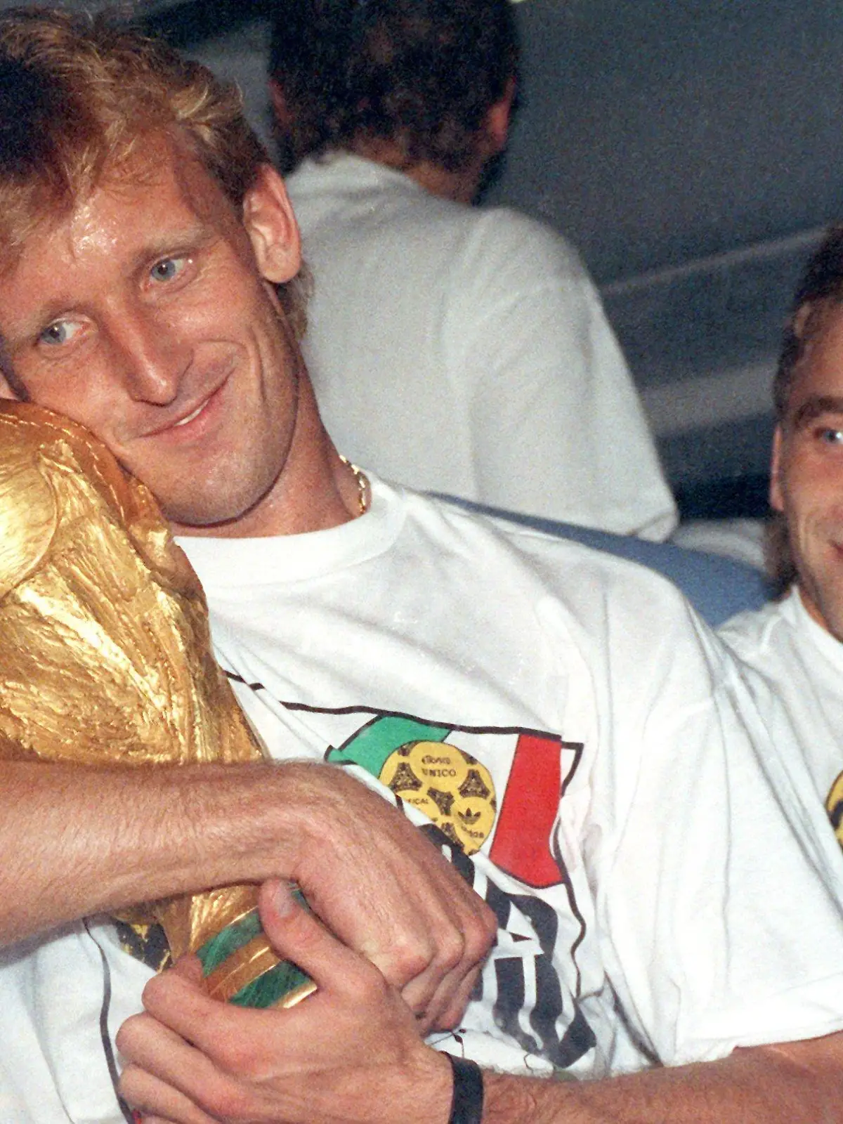 ARCHIV - 09.07.1990, Frankfurt/Main: Andreas Brehme (l), damaliger deutscher Fußballnationalspieler nimm den WM-Pokal in den Arm und sein Teamgefährte Thomas Häßler schaut lächelnd zu. (zu dpa: «Von Illgner bis Völler: Zwölf Helden in der magischen Nacht von Rom») Foto: picture alliance / Frank Kleefeldt/dpa +++ dpa-Bildfunk +++