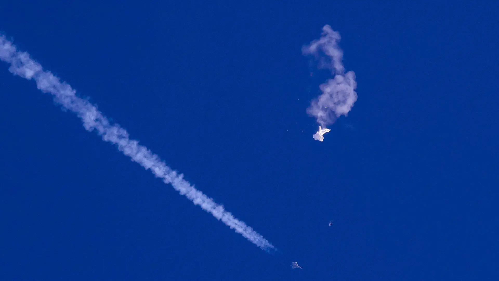 dpatopbilder - 04.02.2023, USA, -: Auf diesem von Chad Fish zur Verfügung gestellten Bild schweben die Überreste eines großen Ballons über dem Atlantischen Ozean vor der Küste South Carolinas. Darunter sind ein Kampfjet und seine Kondensstreifen zu sehen. Der Ballon wurde von einer infrarotgesteuerten Luft-Luft-Rakete des Typs AIM-9X Sidewinder von einem F-22-Kampfflugzeug aus einer Höhe von 58.000 Fuß (etwa 17,7 km) in der Nähe von Myrtle Beach abgeschossen und faszinierte die Himmelsbeobachter in dem bevölkerungsreichen Gebiet, das wegen seiner kilometerlangen Strände, die Rentner und Urlauber anziehen, als Grand Strand bekannt ist. Foto: Chad Fish/Chad Fish/AP/dpa - ACHTUNG: Nur zur redaktionellen Verwendung und nur mit vollständiger Nennung des vorstehenden Credits bis zum 20. Februar 2023. +++ dpa-Bildfunk +++