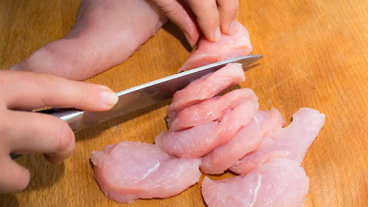 Rohes Hähnchenfleisch wird geschnitten.