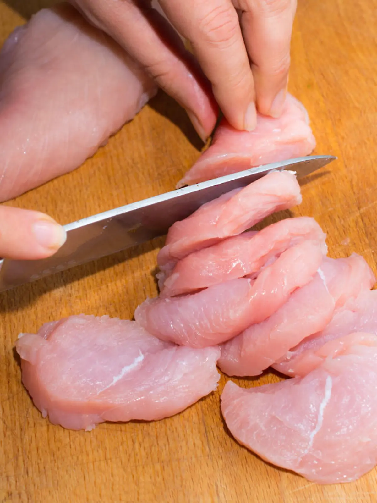 Rohes Hähnchenfleisch wird geschnitten.