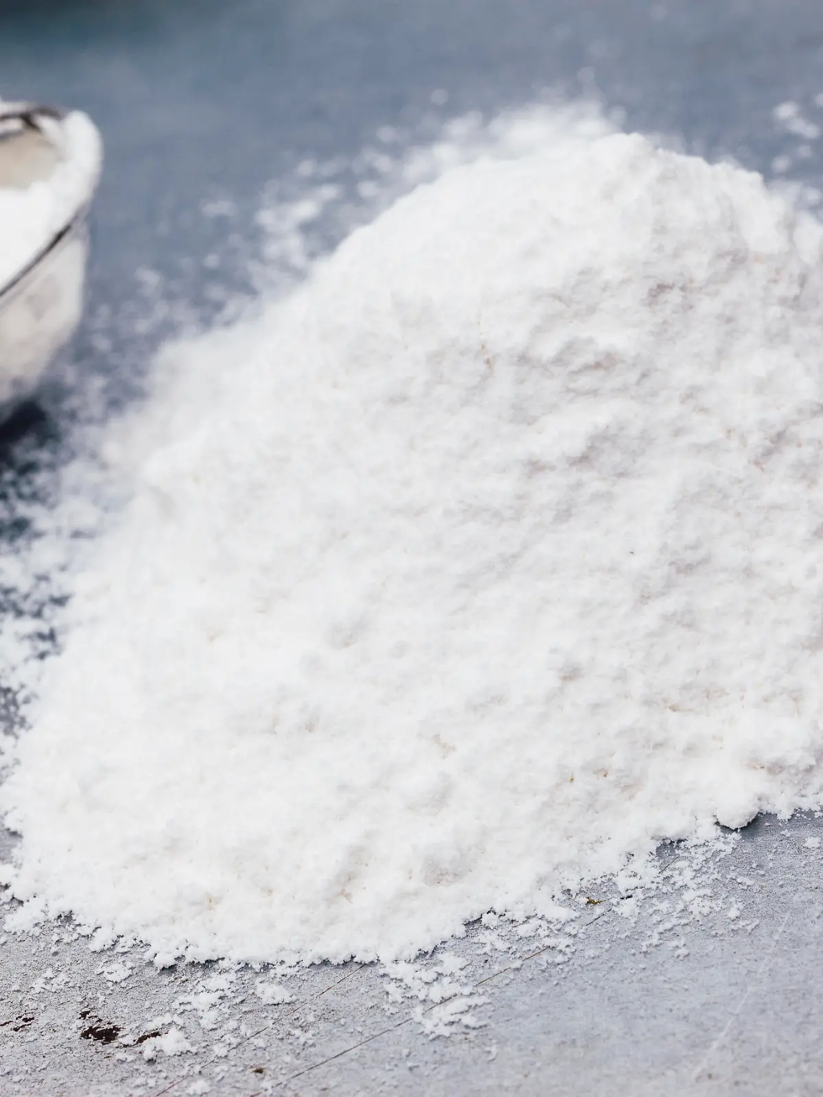 Heap of baking soda with measuring spoon on a metal baking tray.