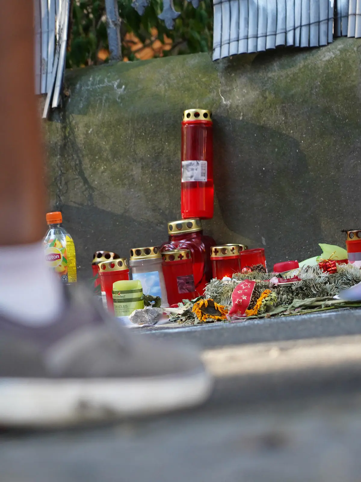 ARCHIV - 12.08.2022, Nordrhein-Westfalen, Dortmund: Menschen stehen vor einem Zaun, an dem mit Kerzen und Blumen eines von der Polizei erschossenen Jugendlichen gedacht wird. Nach den tödlichen Schüssen aus einer Maschinenpistole auf einen 16-Jährigen in Dortmund wird gegen vier weitere Polizisten ermittelt. Dabei geht es um den Einsatz von Pfefferspray und Tasern. Foto: Gregor Bauernfeind/dpa +++ dpa-Bildfunk +++