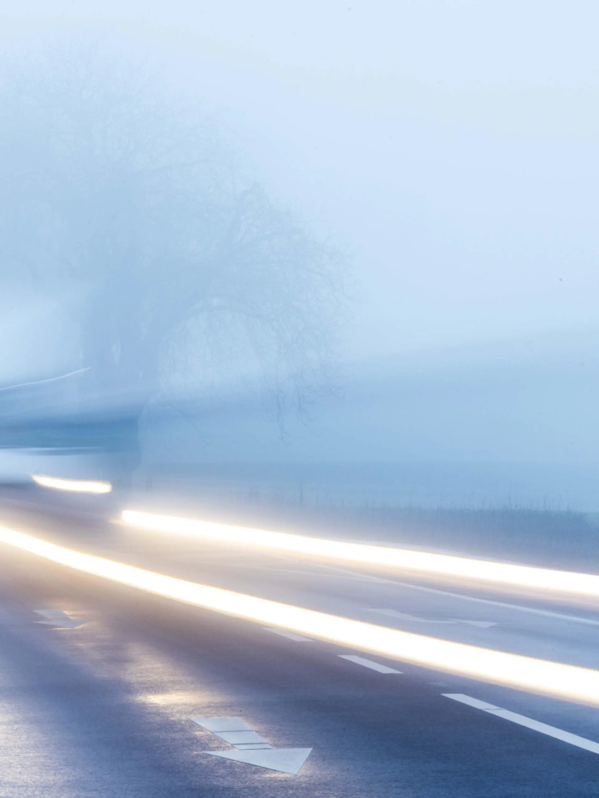 26.01.2023, Mecklenburg-Vorpommern, Mühlen Eichsen: Ein Kleintransporter fährt bei dichtem Nebel durch eine Allee. (Aufnahme mit langer Belichtungszeit) Mit Temperaturen um die null Grad, Nieselregen und teilweise dichtem Nebel zeigt sich das Winterwetter in Norddeutschland von seiner unfreundlichen Seite. Foto: Jens Büttner/dpa +++ dpa-Bildfunk +++
