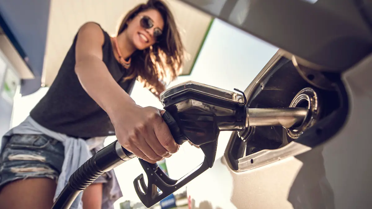 Close up of a beautiful woman refueling the gas tank at fuel pump.