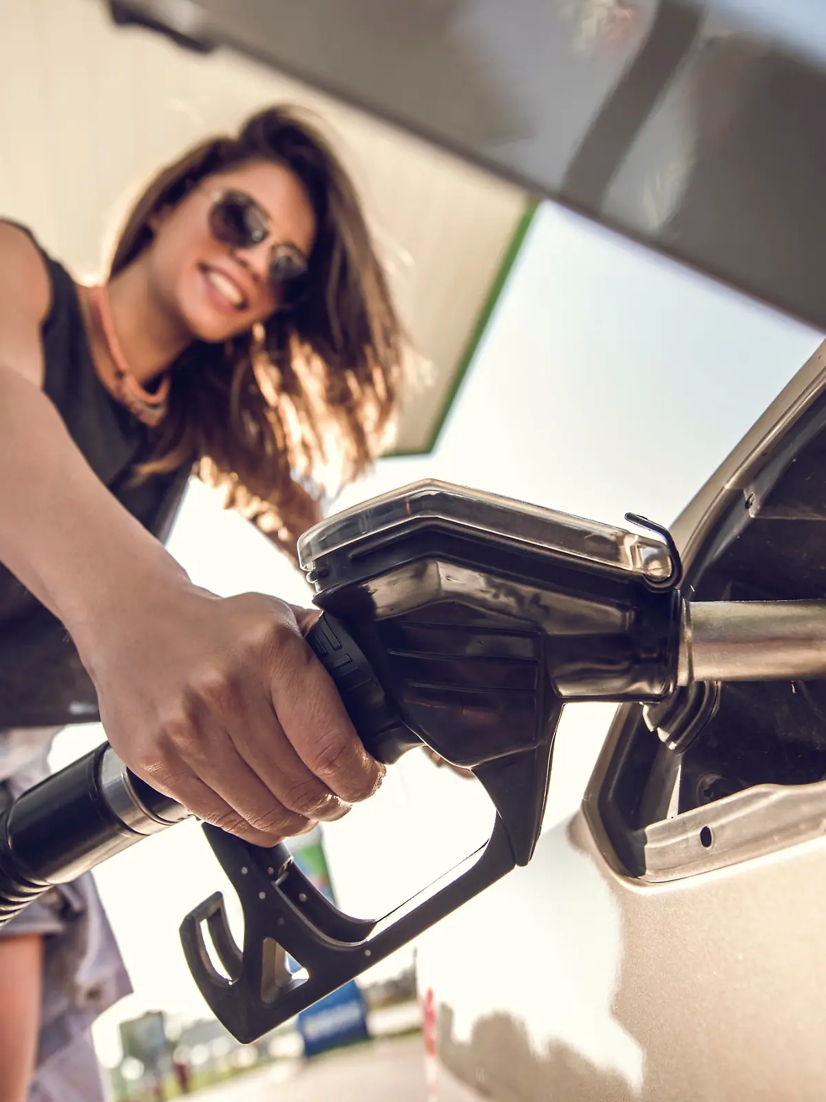 Close up of a beautiful woman refueling the gas tank at fuel pump.