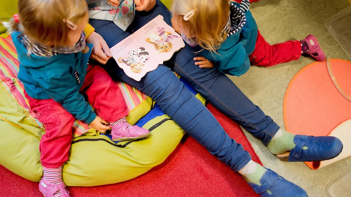 ARCHIV - Eine Erzieherin liest am 16.10.2013 mit Zwillingen ein Buch in einer Kindertagesstätte der Arbeiterwohlfahrt (AWO) in Hannover (Niedersachsen). Trotz leichter Verbesserungen belegen die niedersächsischen Krippen beim Betreuungsschlüssel im bundesweiten Vergleich nur den vorletzten Platz. Foto: Julian Stratenschulte/dpa (zu lni "Studie: Krippenbetreuung in Bremen sehr gut - Niedersachsen schlecht" vom 24.08.2015) +++(c) dpa - Bildfunk+++