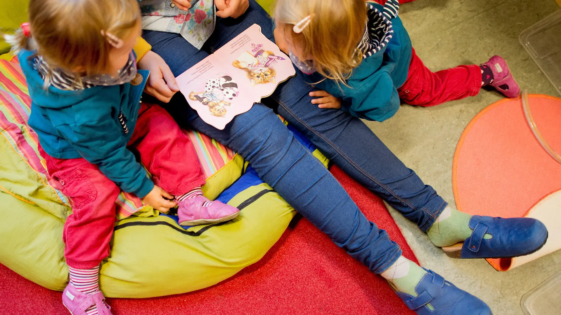 ARCHIV - Eine Erzieherin liest am 16.10.2013 mit Zwillingen ein Buch in einer Kindertagesstätte der Arbeiterwohlfahrt (AWO) in Hannover (Niedersachsen). Trotz leichter Verbesserungen belegen die niedersächsischen Krippen beim Betreuungsschlüssel im bundesweiten Vergleich nur den vorletzten Platz. Foto: Julian Stratenschulte/dpa (zu lni "Studie: Krippenbetreuung in Bremen sehr gut - Niedersachsen schlecht" vom 24.08.2015) +++(c) dpa - Bildfunk+++