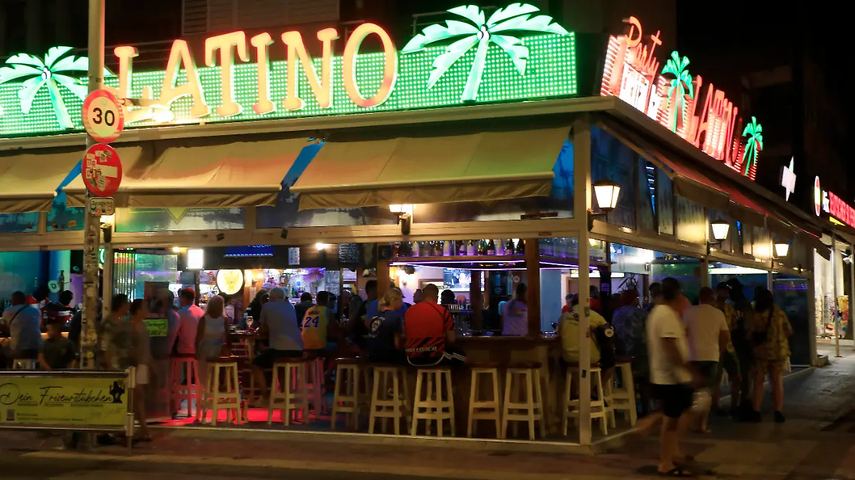 09.07.2023, Spanien, Palma: Menschen halten sich auf der «Latino»-Terrasse in der Straße Carrer Llaut am Strand von Arenal auf. Foto: Clara Margais/dpa +++ dpa-Bildfunk +++