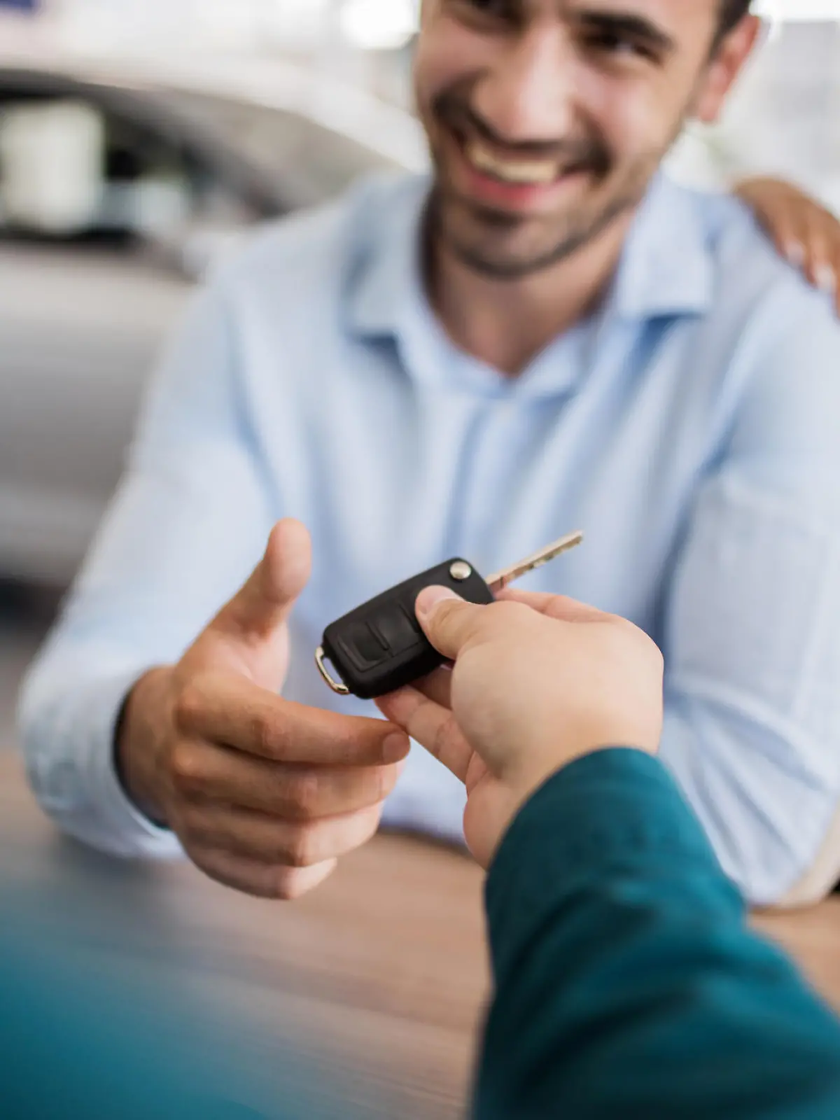 Close up of couple receiving key of a new car at car dealership.