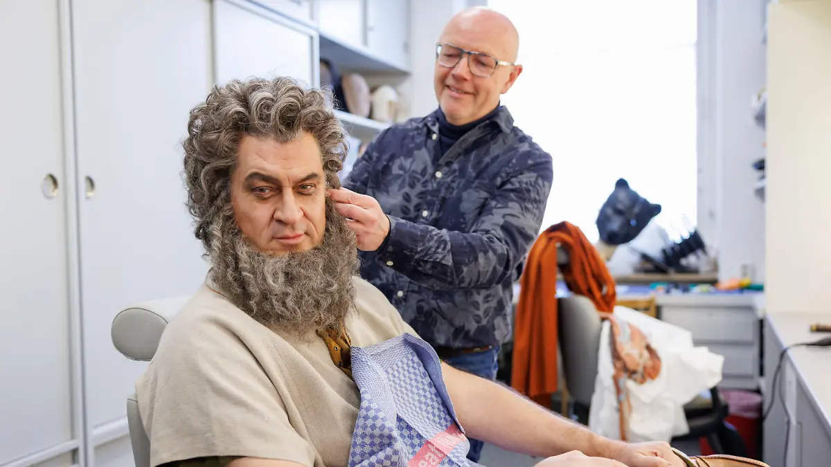 PRODUKTION - 10.02.2023, Bayern, Nürnberg: Markus Söder (l, CSU), Ministerpräsident von Bayern, wird in der Maske im Staatstheater Nürnberg als Symbolfigur "Stammesältester, der Bayern sicher durch die Krise führt" von Maskenbildner Armin Häfner verkleidet und geschminkt. Söder wurde dort für die anstehende Fernsehsendung "Fastnacht in Franken" vorbereitet. Foto: Daniel Karmann/dpa +++ dpa-Bildfunk +++
