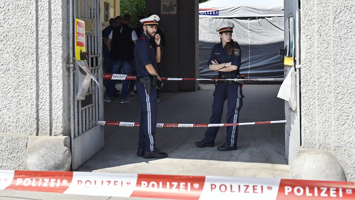 12.05.2018, Österreich, Wien: Polizisten stehen hinter einer Polizeiabsperrung vor einer Wohnhausanlage, nachdem der Leichnam eines Mädchens in einem Müllcontainer entdeckt worden ist. Foto: Hans Punz/APA/dpa +++ dpa-Bildfunk +++
