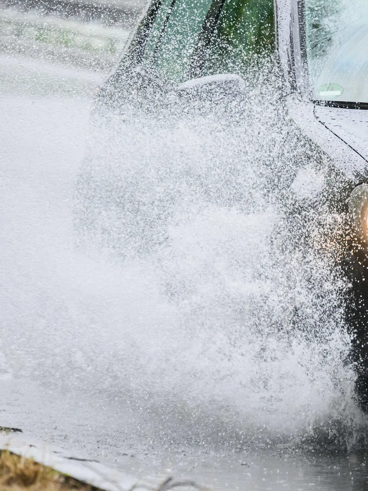 23.06.2023, Niedersachsen, Hannover: Ein Auto fährt durch eine große Regenpfütze an der Hildesheimer Straße. Foto: Julian Stratenschulte/dpa +++ dpa-Bildfunk +++