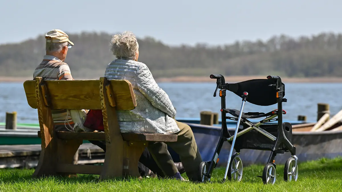 ARCHIV - 22.04.2023, Brandenburg, Storkow: Ein älteres Paar sitzt auf einer Bank am Ufer eines Sees und genießt das sonnige Frühlingswetter. Viele Jahrzehnte lang ist die Lebenserwartung von Frauen schneller gestiegen als die der Männer - seit Ende des 20. Jahrhunderts aber verringert sich dieses Ungleichgewicht laut einer Studie wieder. (zu dpa «Studie: Lebenserwartung von Frauen und Männern nähert sich an») Foto: Patrick Pleul/dpa +++ dpa-Bildfunk +++