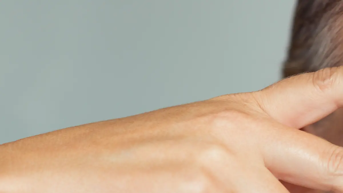 Portrait of smiling senior woman with perfect skin showing victory sign near eye on grey background. Closeup face of mature woman showing successful results after anti-aging wrinkle treatment. Beauty mature skin care concept.