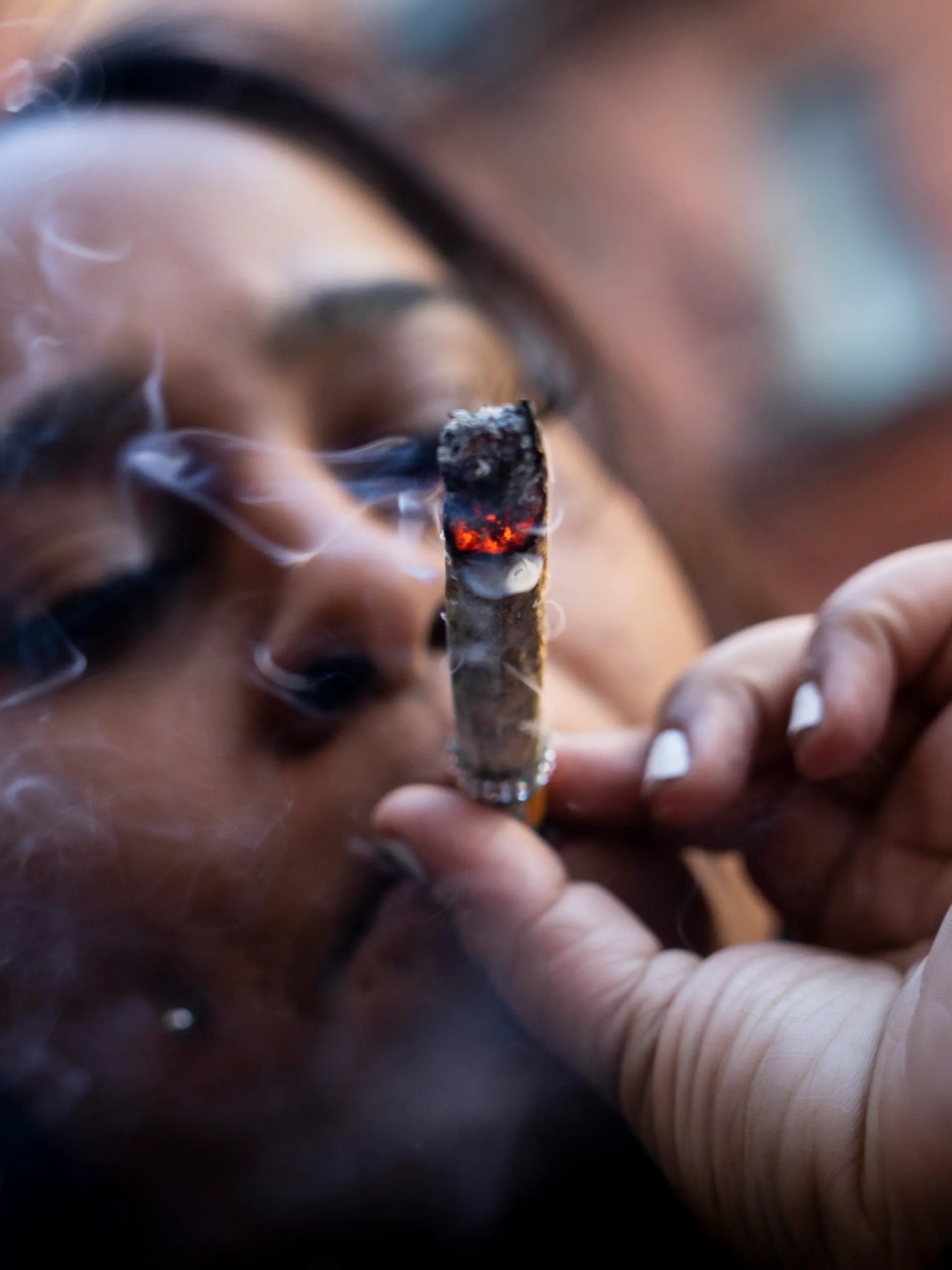 A person smokes cannabis outside the Smacked "pop up" cannabis dispensary location, Tuesday, Jan. 24, 2023, in New York. The store is the first Conditional Adult-Use Retail Dispensary (CAURD) opening since the legalization of cannabis that is run by businesspeople who had been criminalized by cannabis prohibition. (AP Photo/John Minchillo)