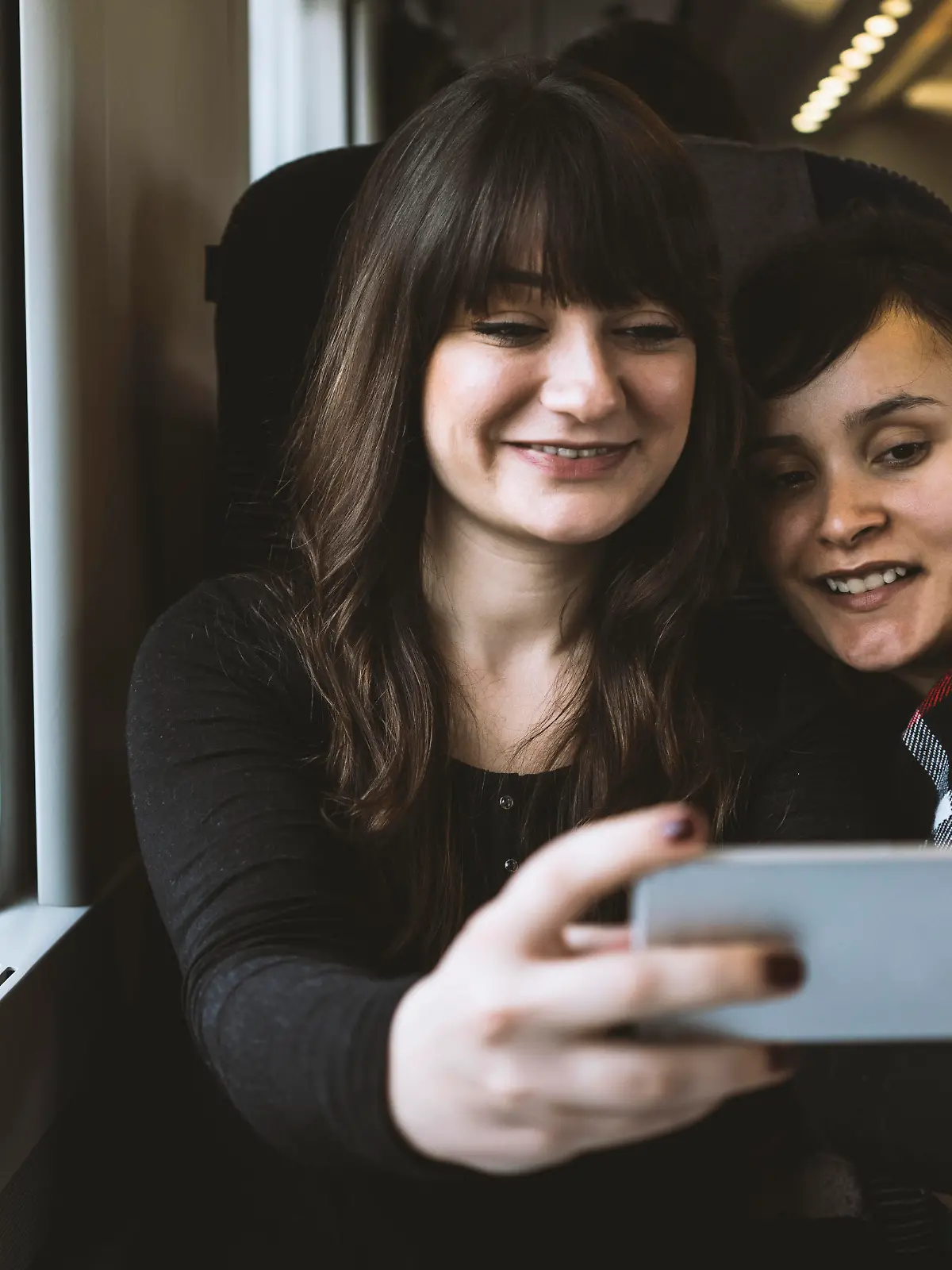 Two young woman taking a selfie on the train.