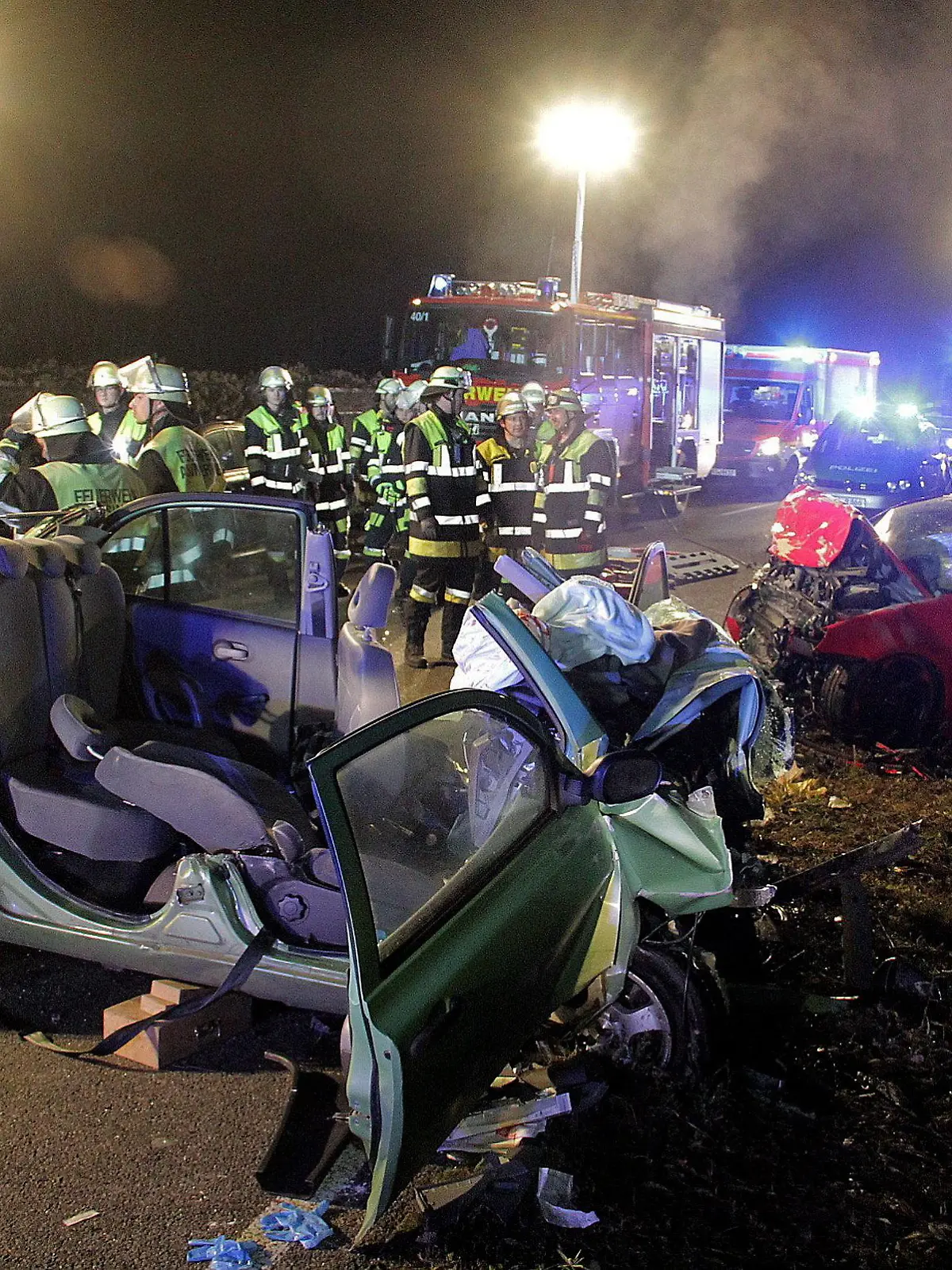 ARCHIV - 20.11.2016, Bayern, Rosenheim: Rettungskräfte und zwei zerstörte Fahrzeuge stehen an einer Unfallstelle. Zwei junge Frauen starben bei dem Unfall, drei Menschen wurden schwer verletzt. Nun müssen sich zwei Männer wegen fahrlässiger Tötung vor Gericht verantworten. (zu dpa «Neuauflage des Prozesses um einen tödlichen Verkehrsunfall» vom 10.04.2018) Foto: Josef Reisner/dpa +++ dpa-Bildfunk +++