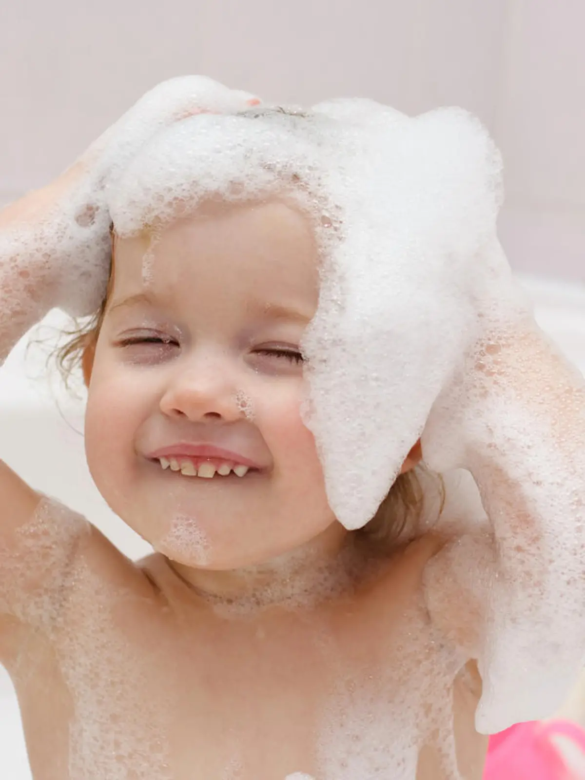 Cute baby is washing her hair in bath 