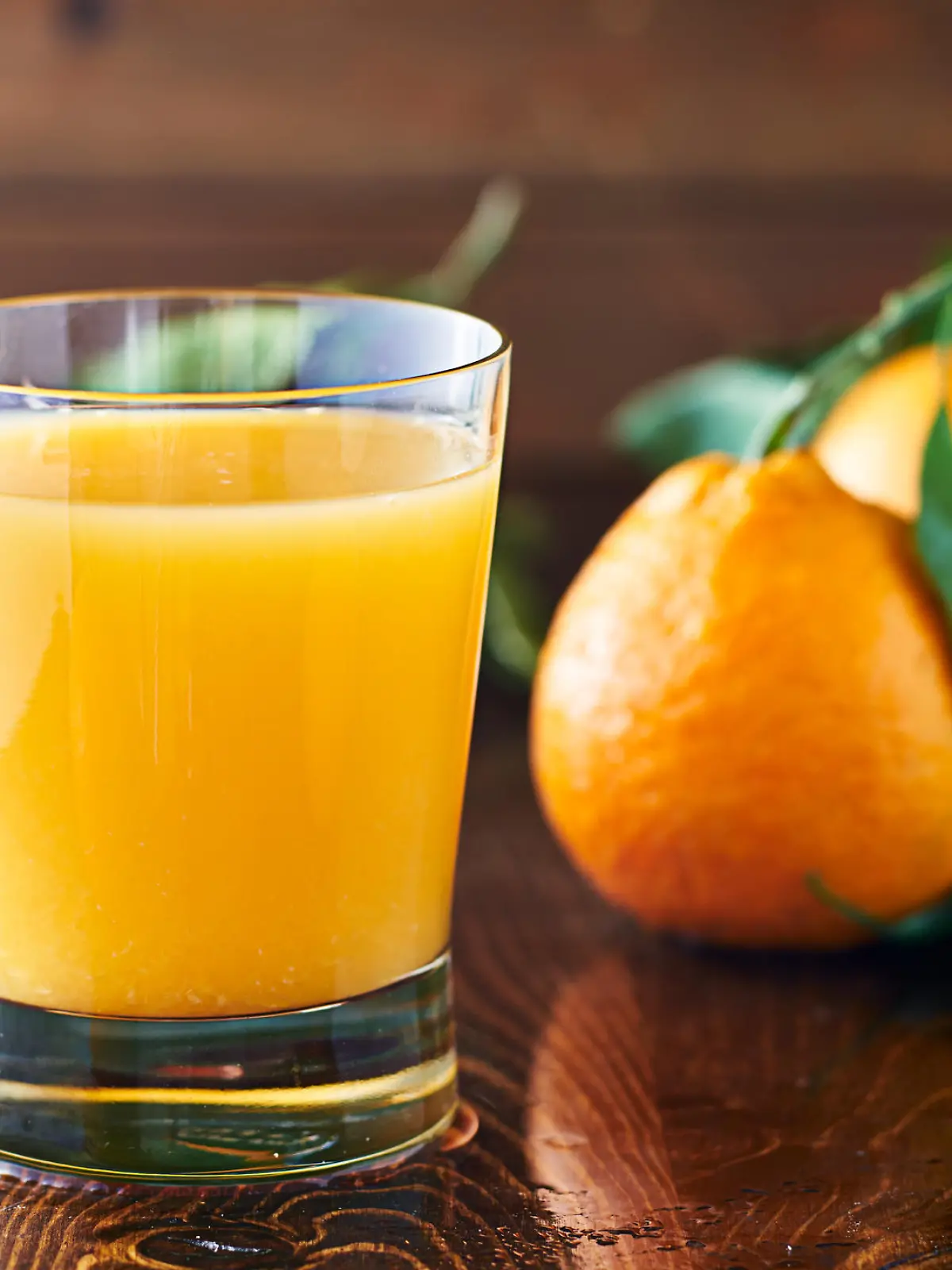 fresh glass of orange juice on rustic table top close up