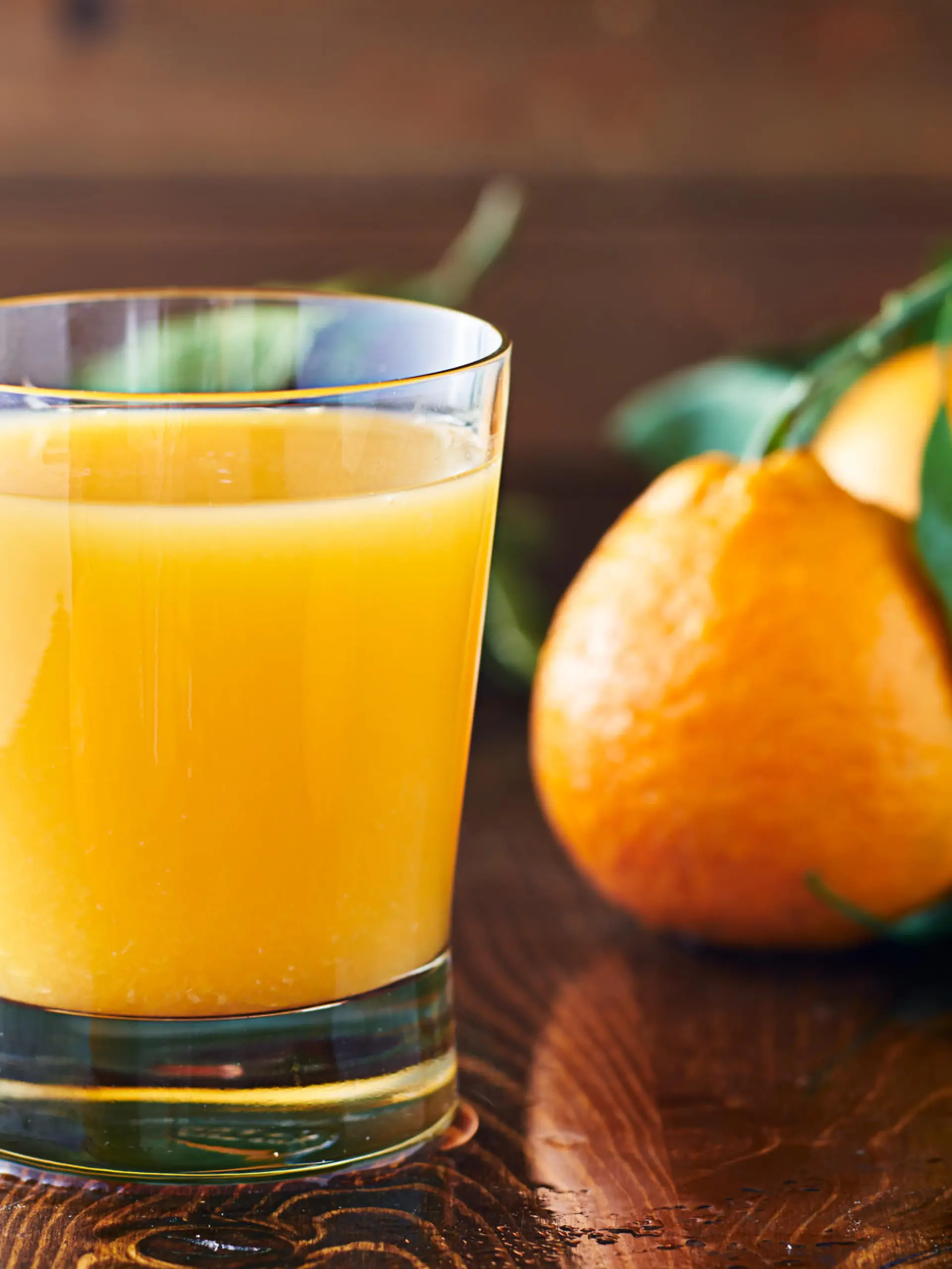 fresh glass of orange juice on rustic table top close up