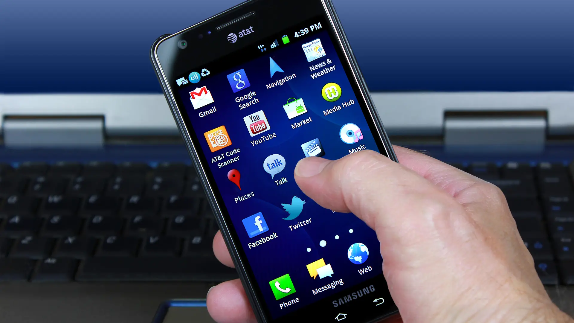 "Palm Springs, USA - April 22, 2012: A hand holding an AT&T/Samsung smartphone displaying social media and touchscreen icons."