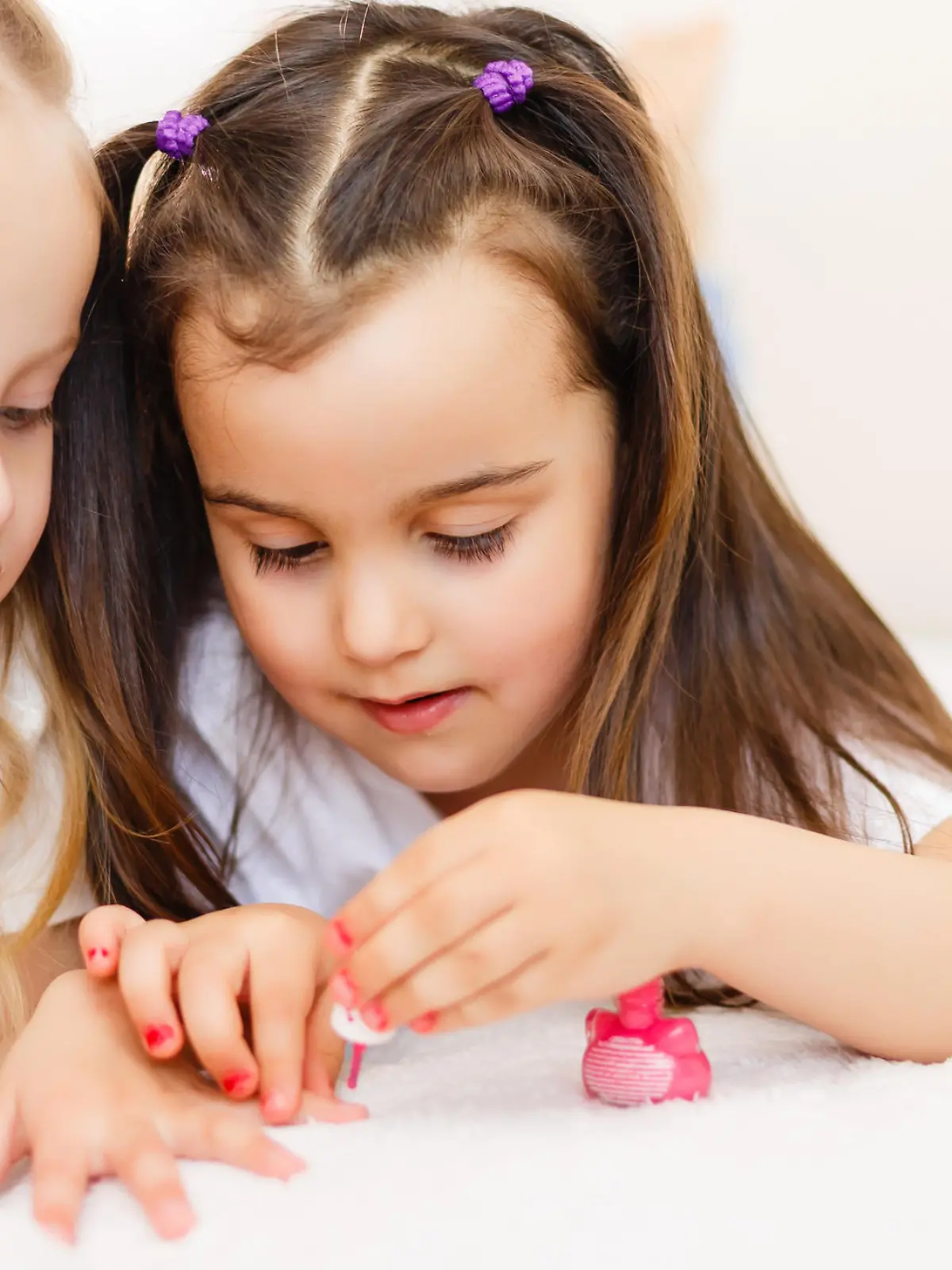 Two little girls painted their nails at home.