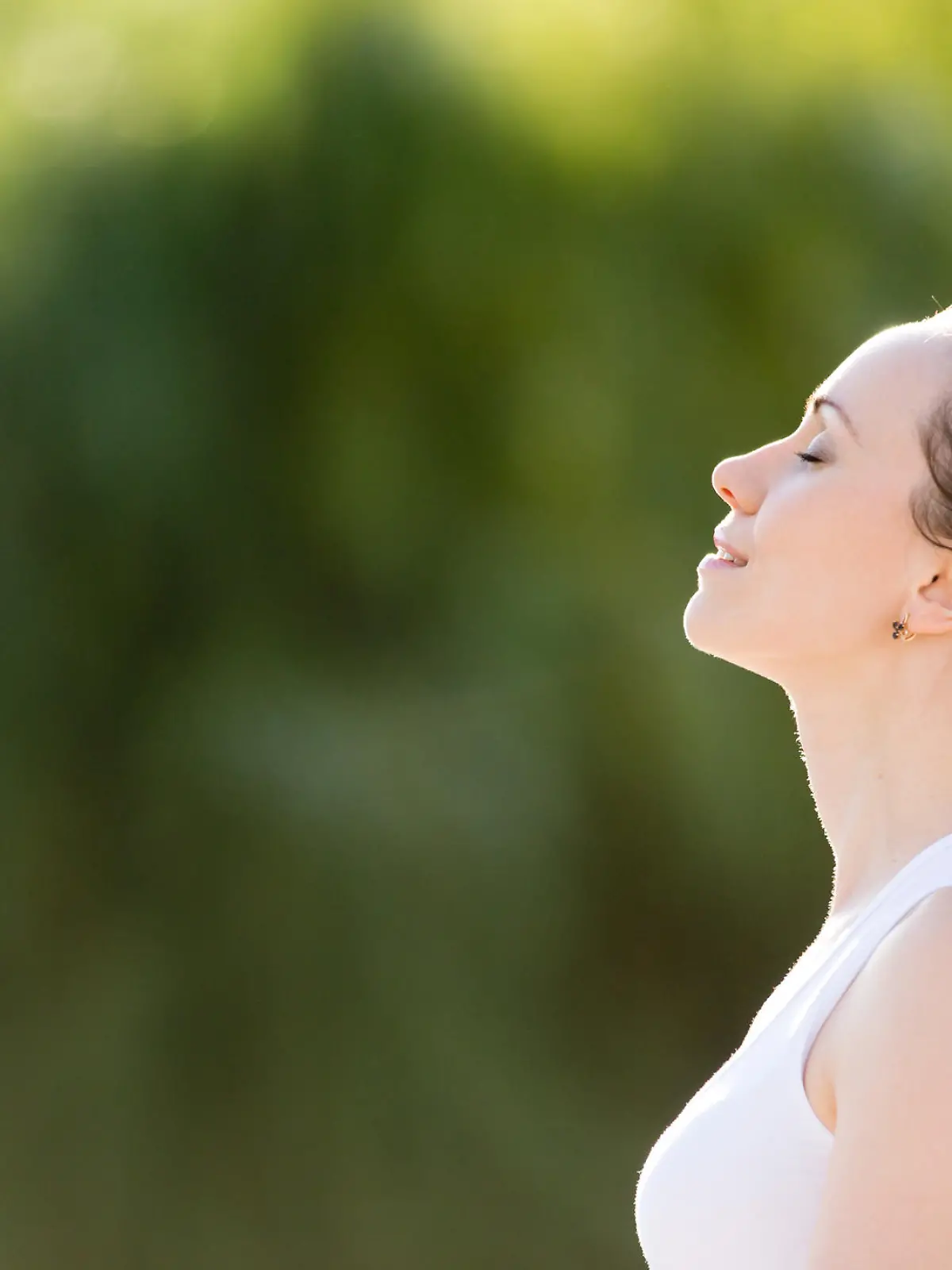 Portrait of beautiful smiling young woman enjoying yoga, relaxing, feeling alive, breathing fresh air, got freedom from work or relations, calm and dreaming with closed eyes, in green park, copy space