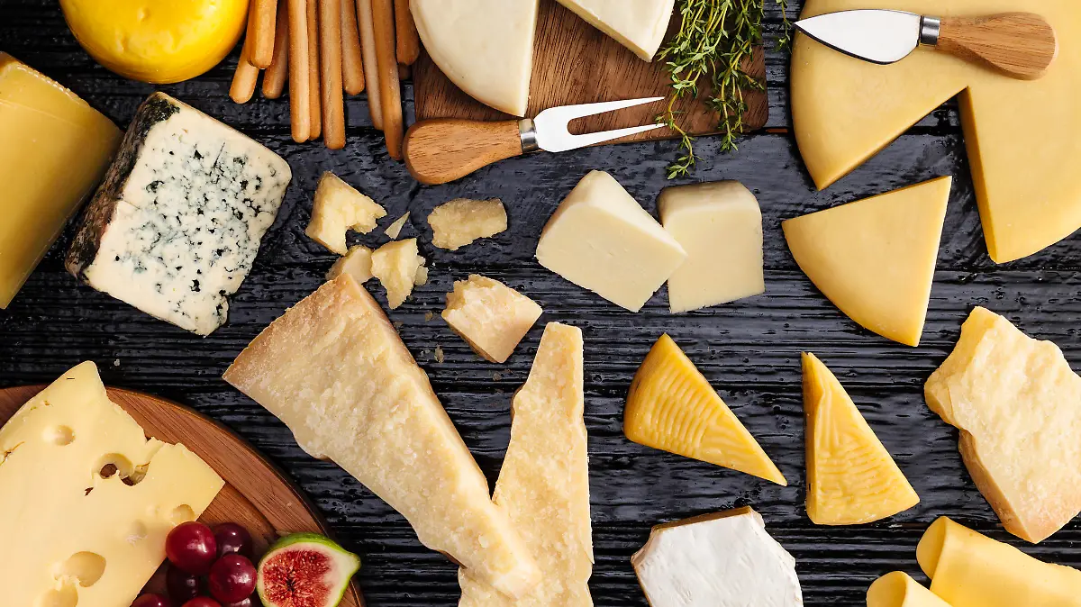 Top view of a dark table filled with a wide variety of cheeses.