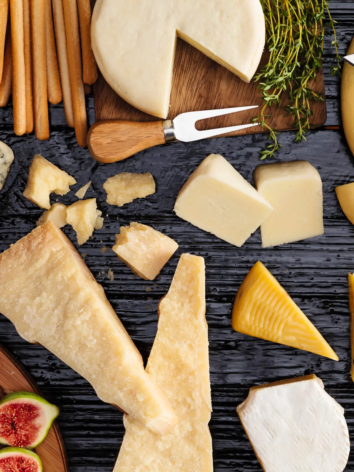 Top view of a dark table filled with a wide variety of cheeses.