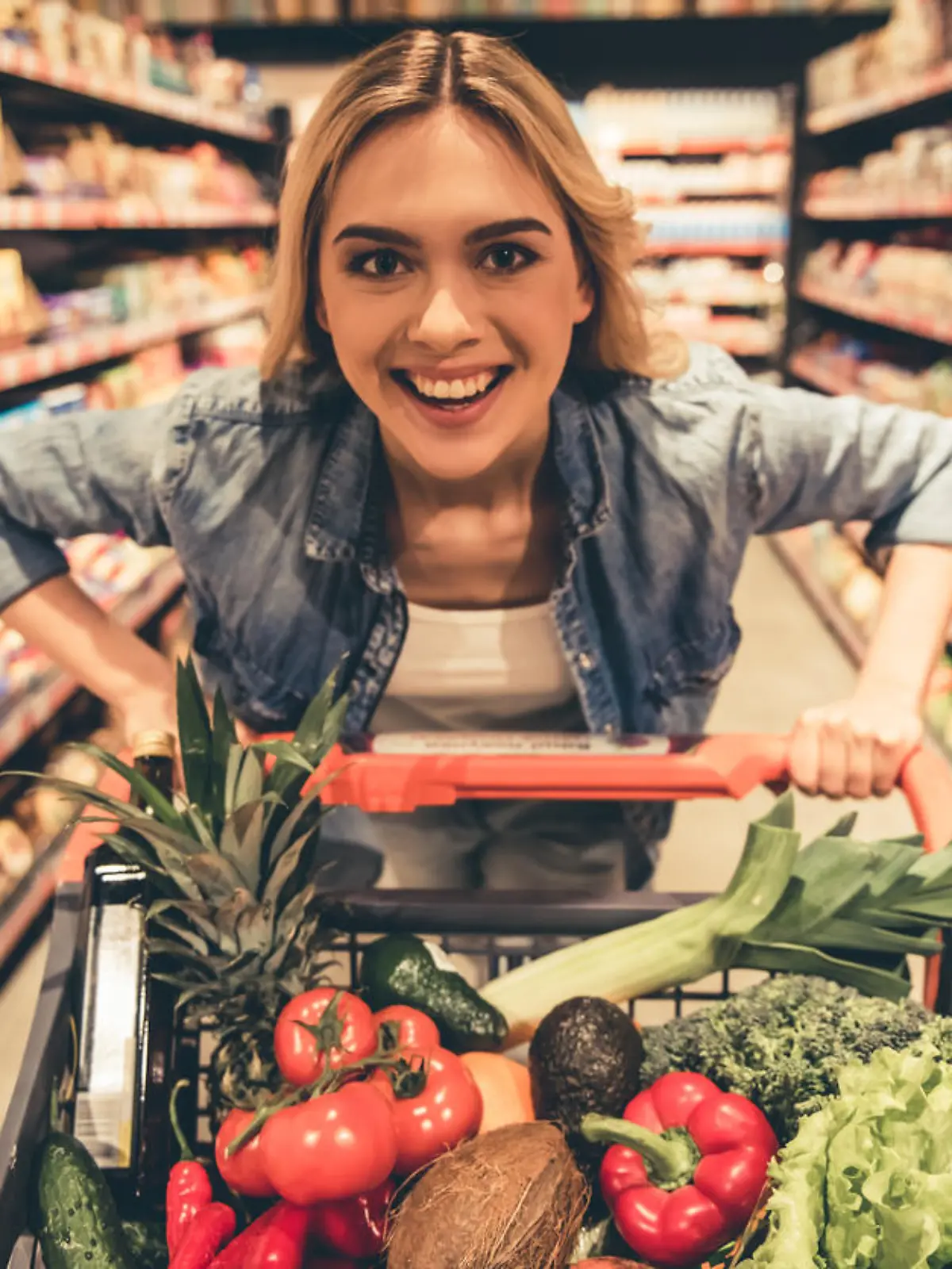 Eine junge Frau mit einem vollen Einkaufswagen im Supermarkt.