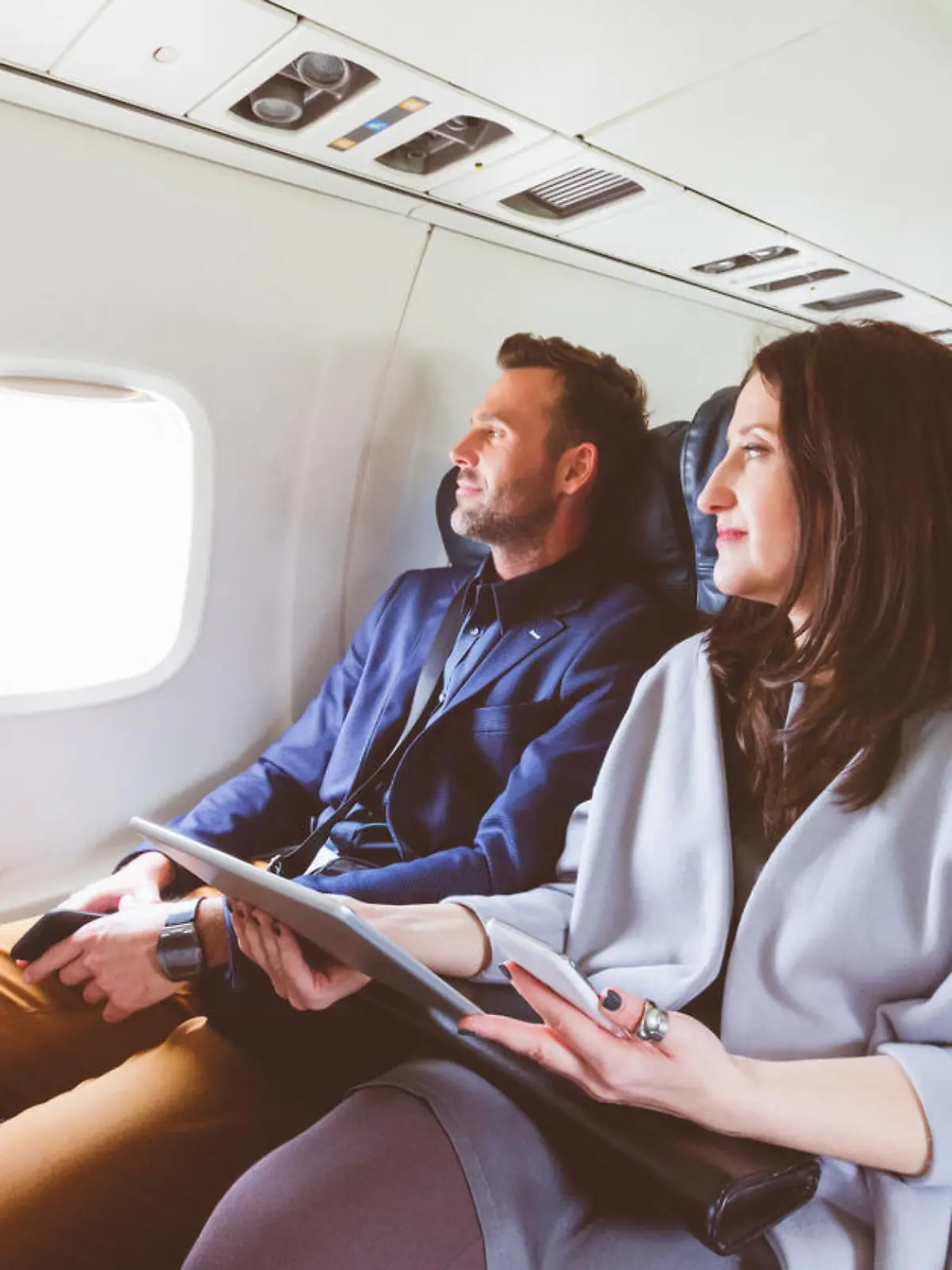 Ein Mann und eine Frau sitzen nebeneinander im Flugzeug.