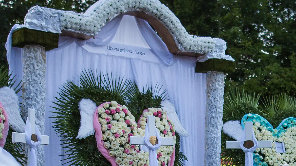 Ein Meer aus Kränzen, Blumen und Gestecken sowie bunte Mickey-Maus-Figuren mit Luftballons sind am 19.08.2017 nach der Trauerfeier und Beerdigung für eine fünfköpfige Familie, die am 11. August auf der Landstraße 361 zwischen Nagold und Mötzingen (Baden-Württemberg) von einem umgestürzten Müllwagen getötet wurde, am Grab auf dem Friedhof in Mötzingen (Baden-Württemberg) zu sehen. (zu dpa "Trauerfeier mit Applaus - Opfer des Müllwagen-Unglücks beerdigt" am 19.08.2017) Foto: Christoph Schmidt/dpa +++(c) dpa - Bildfunk+++