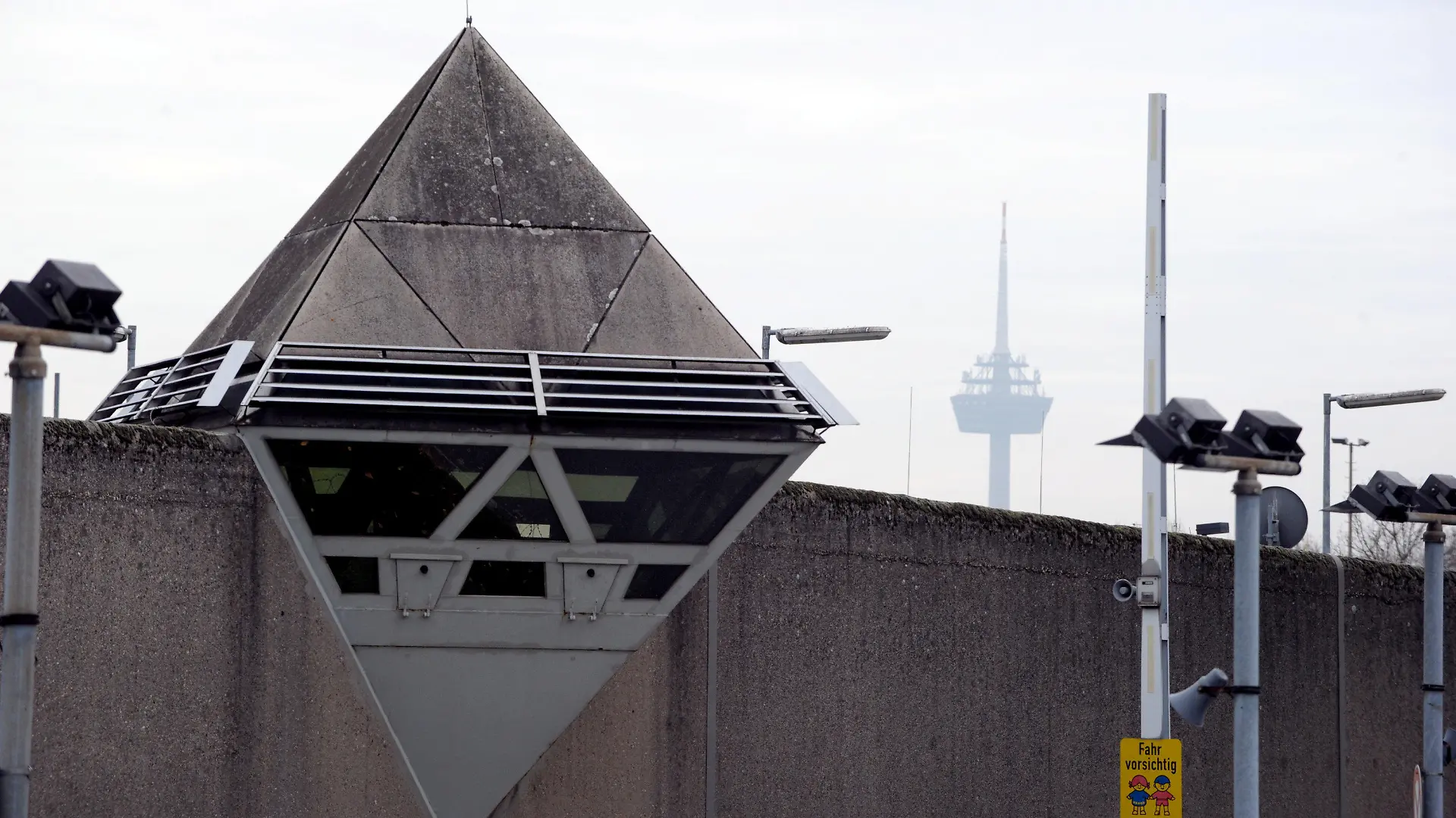 ARCHIV - 18.11.2011, Nordrhein-Westfalen, Köln: Wachtürme und Sicherheitskameras sind auf der Mauer der Justizvollzugsanstalt Ossendorf zu sehen. (zu dpa: "Gefangener bei Feuer in der JVA Köln schwer verletzt") Foto: Federico Gambarini/dpa +++ dpa-Bildfunk +++