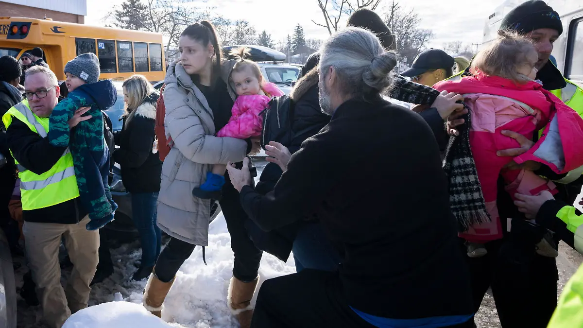 Parents and their children are loaded onto a warming bus as they wait for news after a bus crashed into a daycare centre in Laval, Quebec, on Wednesday, Feb. 8, 2023. (Ryan Remiorz/The Canadian Press via AP)