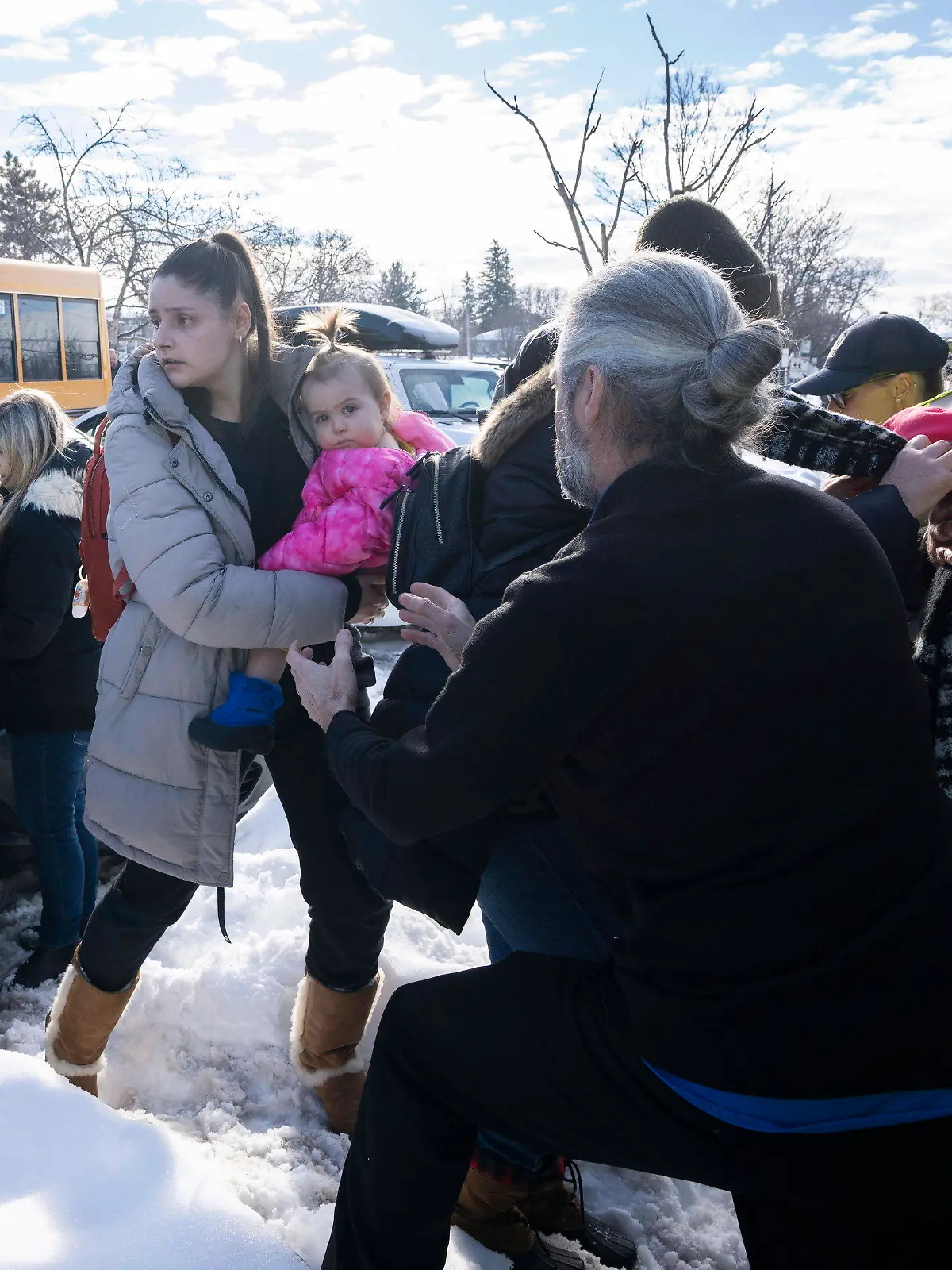 Parents and their children are loaded onto a warming bus as they wait for news after a bus crashed into a daycare centre in Laval, Quebec, on Wednesday, Feb. 8, 2023. (Ryan Remiorz/The Canadian Press via AP)